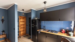 A modern kitchen with dark cabinets, a wooden countertop, and a built-in stove. - Vintage Apartments BLACK / Free parking (Riga)