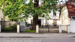 A gated parking area with a tree and a building in the background. - Vintage Apartments BLACK / Free parking (Riga)