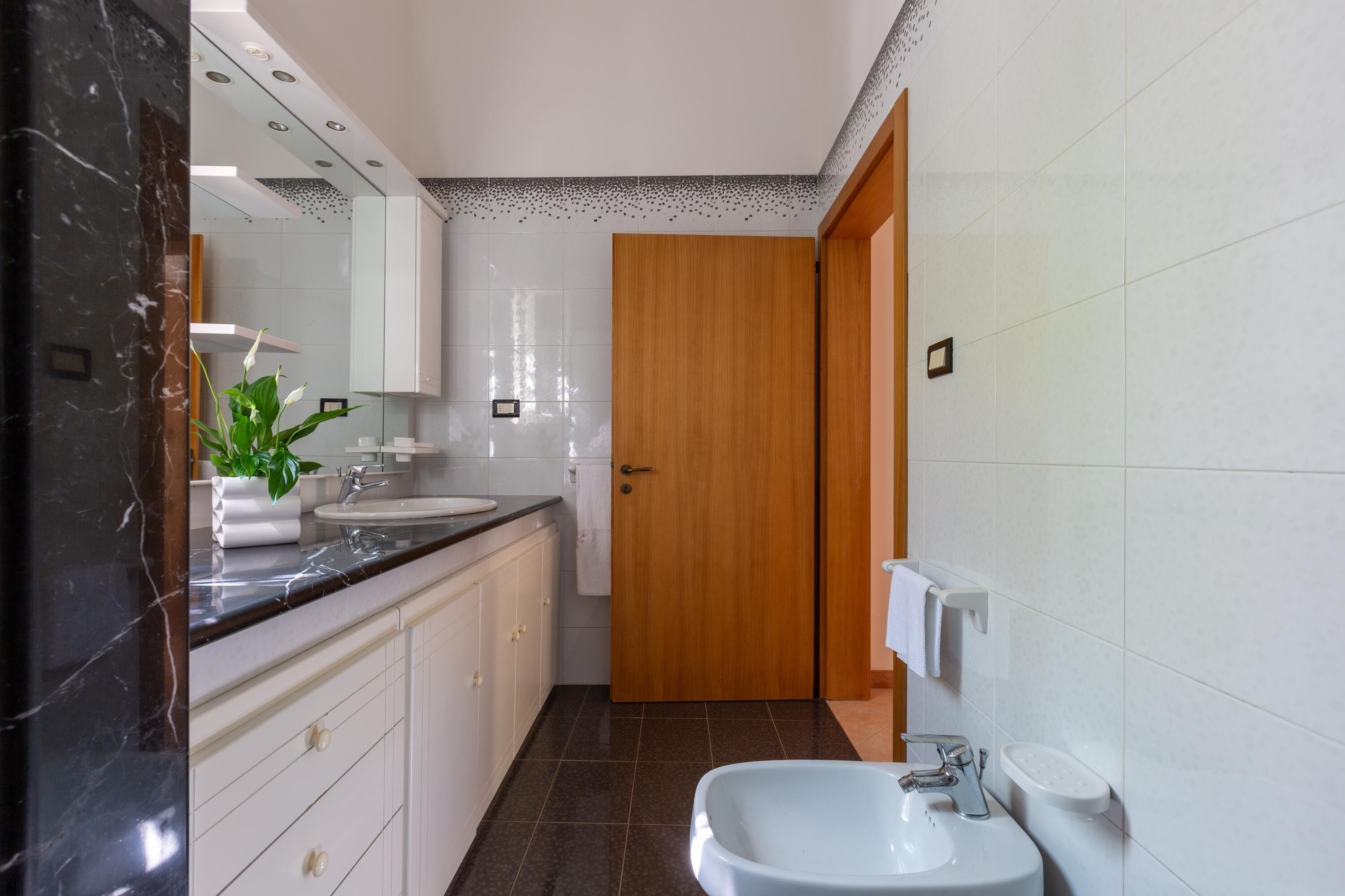 Un baño moderno con dos lavamanos, un espejo grande y una puerta de madera.