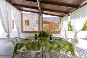 An outdoor dining area with a checkered tablecloth, white chairs, and a basket of greenery. - 2497 Villa Cielo e Terra by Barbarhouse (Racale)
