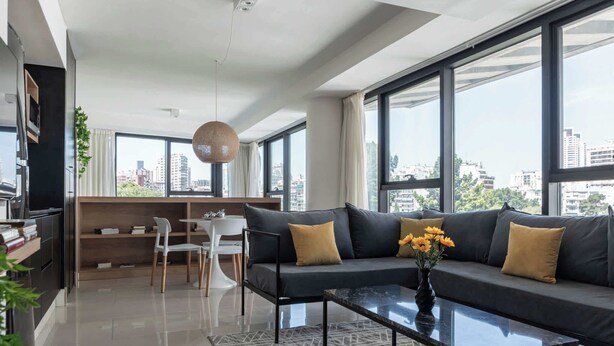 En moderne stue med sofa, sofabord og spiseplads med et hvidt bord og stole.