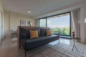 Ein modernes Wohnzimmer mit einer Couch, einem kleinen Tisch und Blick ins Freie.
