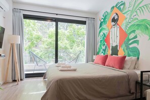 Ein modernes Hotelzimmer mit einem großen Bett, Blick auf Grünflächen und einer einzigartigen Wandmalerei.