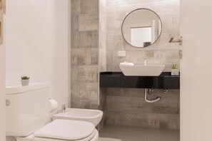 Ein modernes Badezimmer mit Toilette, Bidet und Waschbecken in Weiß.