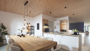 Une cuisine moderne avec un îlot central en bois, des meubles blancs et des luminaires suspendus.