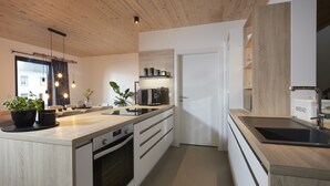 Une cuisine moderne avec des meubles en bois, un four encastré, un évier et un plan de travail agrémenté de plantes en pot.