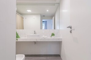 A modern bathroom with a white sink, mirror, and a shower curtain.