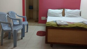 Ein Schlafzimmer mit einem Bett, zwei Stühlen, einem Kleiderschrank und einer roten Wand.