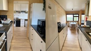 Una cuina moderna amb parets de fusta, un rellotge i una zona de menjador amb vistes.