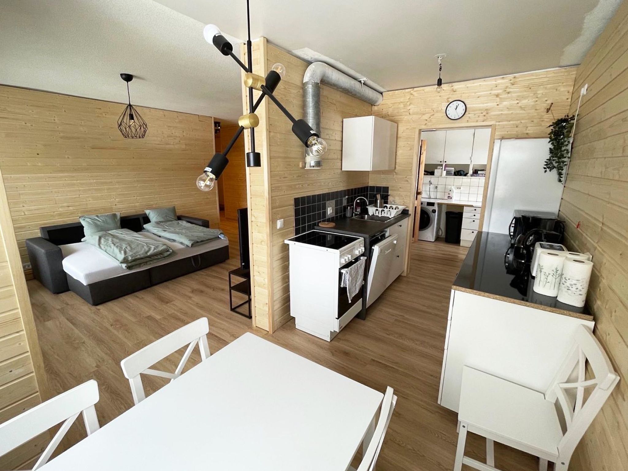 Cocina compacta con comedor, kitchenette y zona de descanso con sofá y cama.