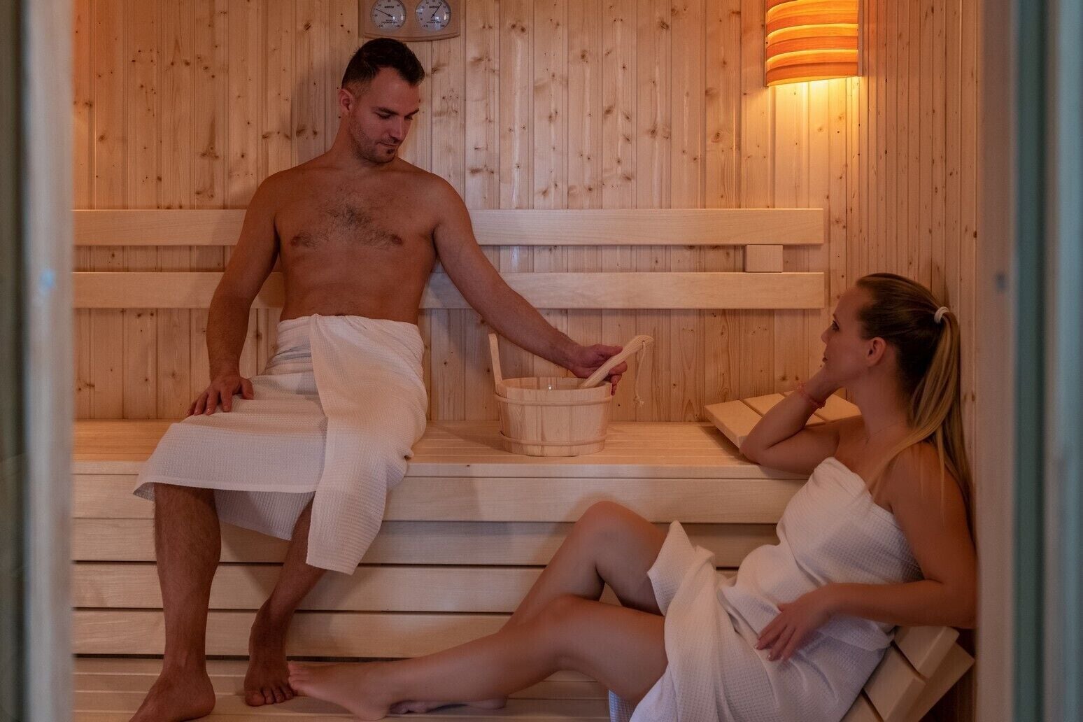 A sauna with wooden benches and a bucket.