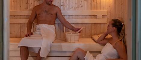 A sauna with wooden benches and a bucket.