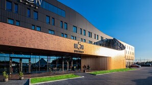 Un hotel moderno con un llamativo letrero 'FLOW', un acceso cubierto y un estacionamiento.