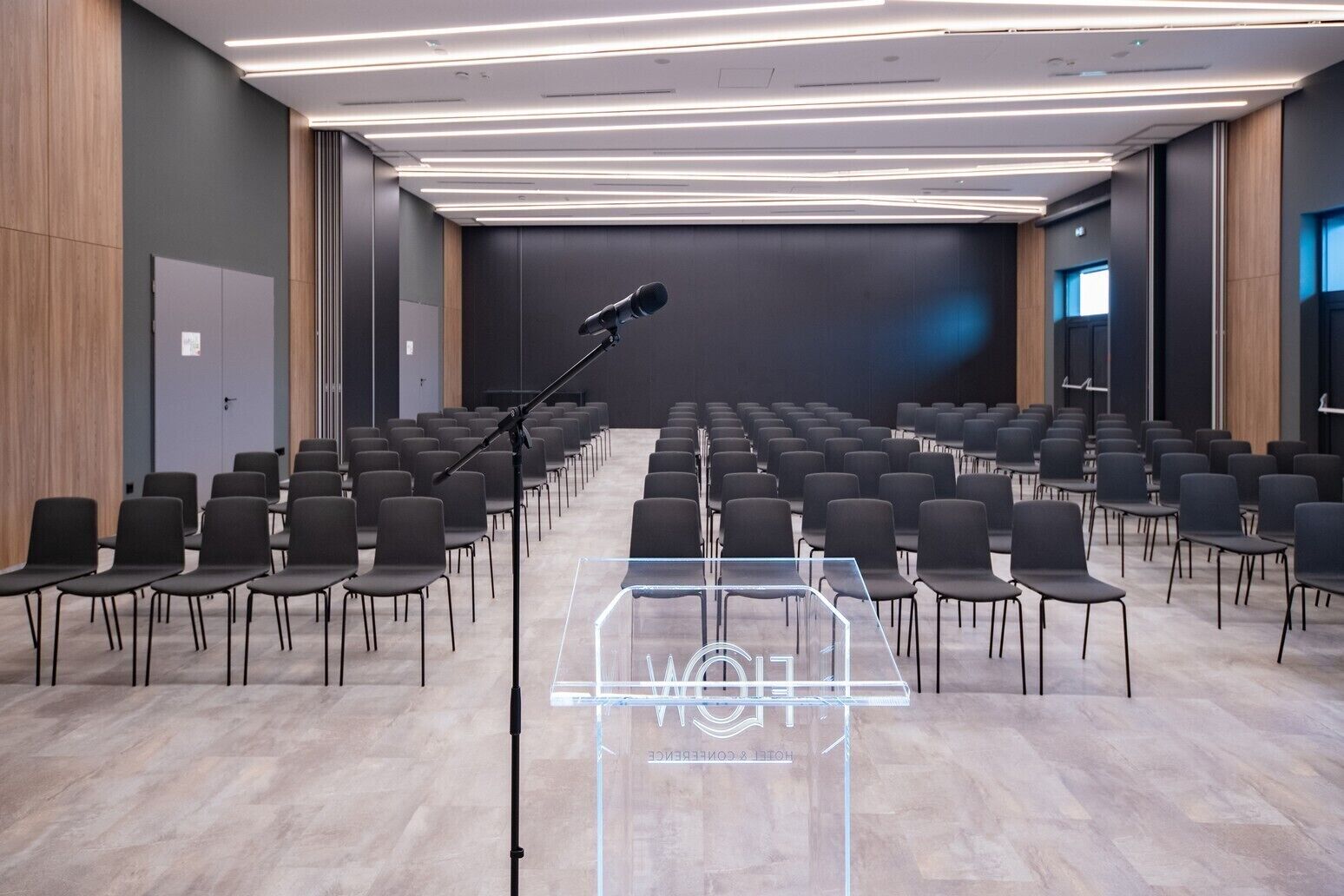 Un salón de conferencias con filas de sillas, un atril y un micrófono.