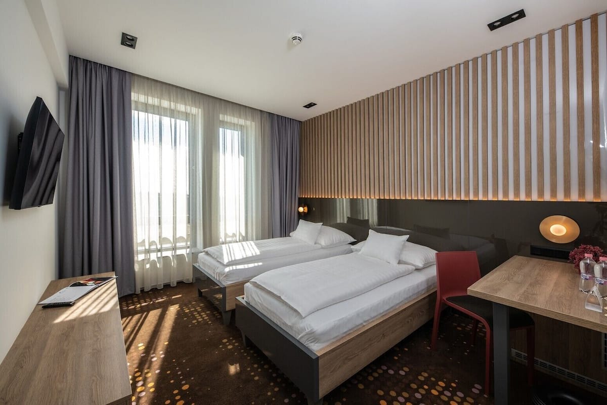 Una habitación de hotel con dos camas, un escritorio, una silla y un televisor.