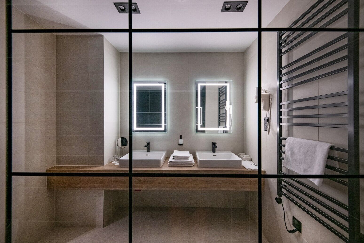 A modern bathroom with two sinks, a mirror, and a towel rack.