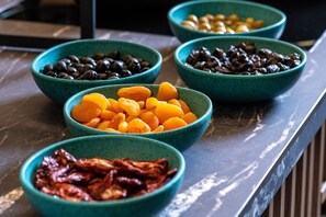 A table with five bowls containing different dried fruits.