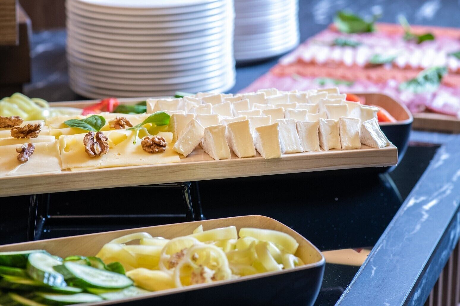 Un bufé con diversos alimentos, incluyendo queso, frutos secos y verduras en rodajas.