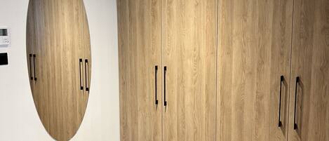 A room with a wooden wardrobe, a circular mirror, and a patterned carpet.
