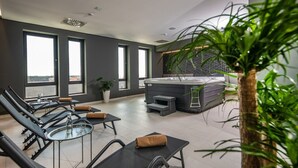 Un espacio interior moderno para relajarse, con tumbonas, un jacuzzi y ventanas amplias con vistas.