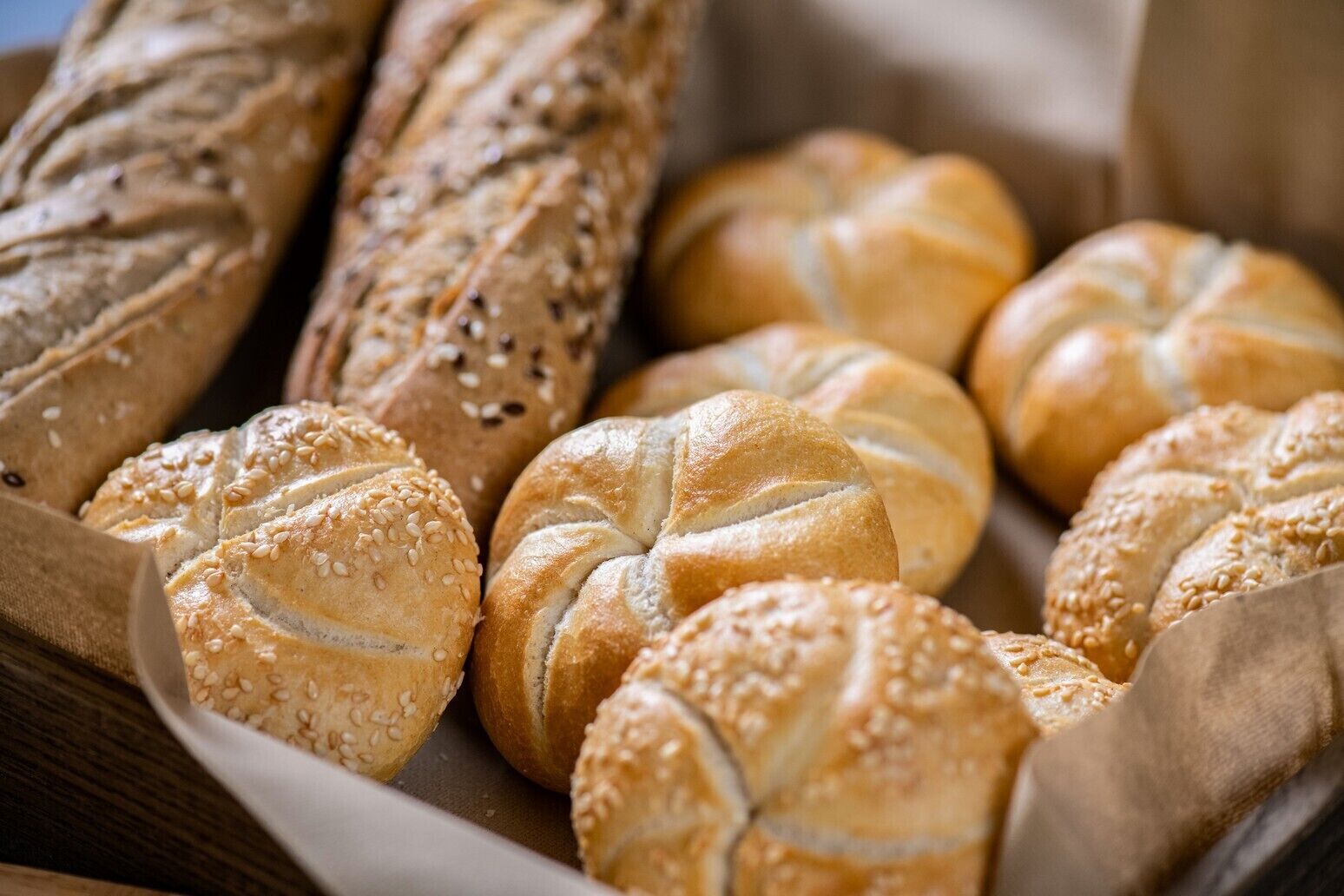A variety of breads, including rolls and baguettes, arranged on a wooden surface.
