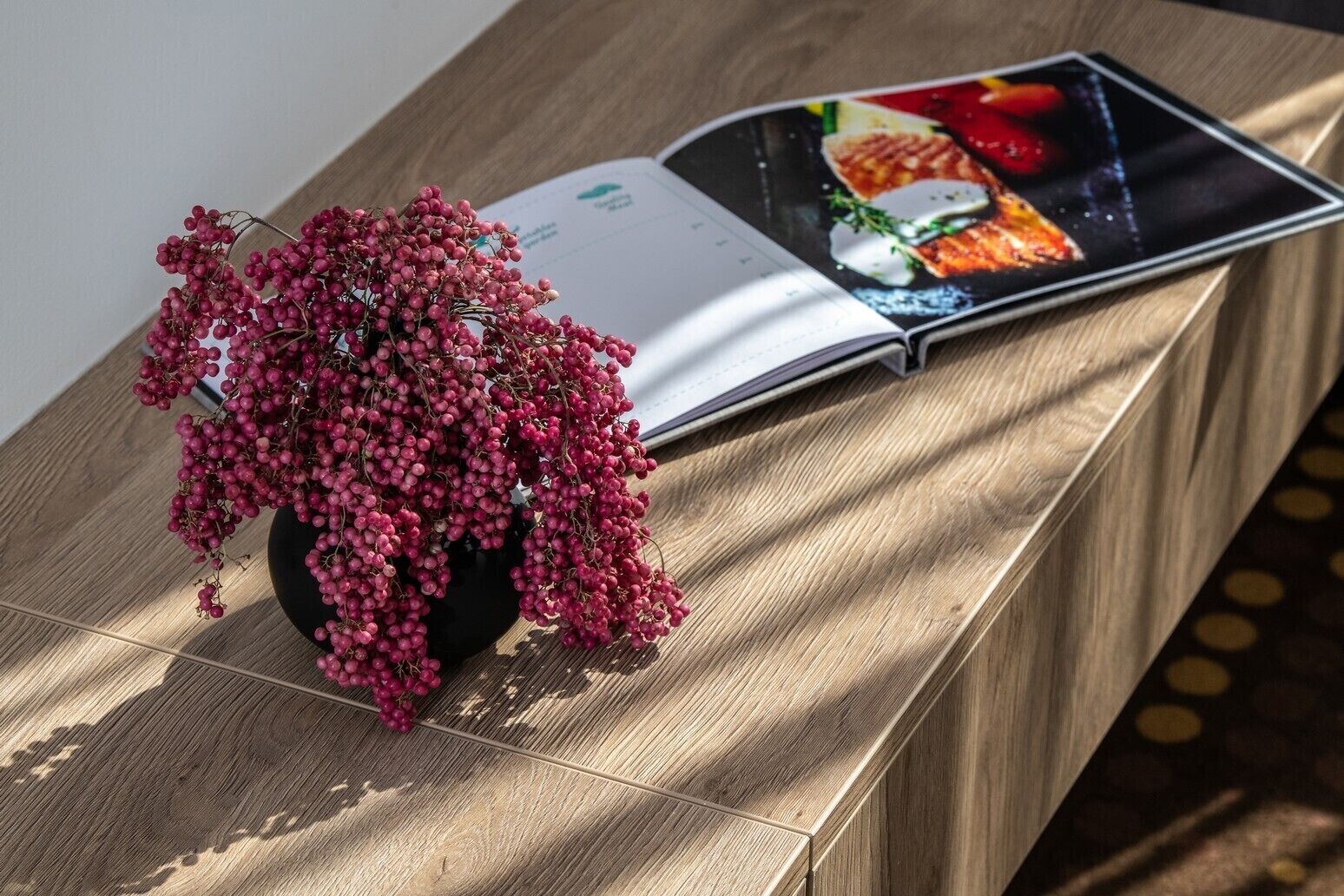 A wooden table with a potted plant and an open magazine.