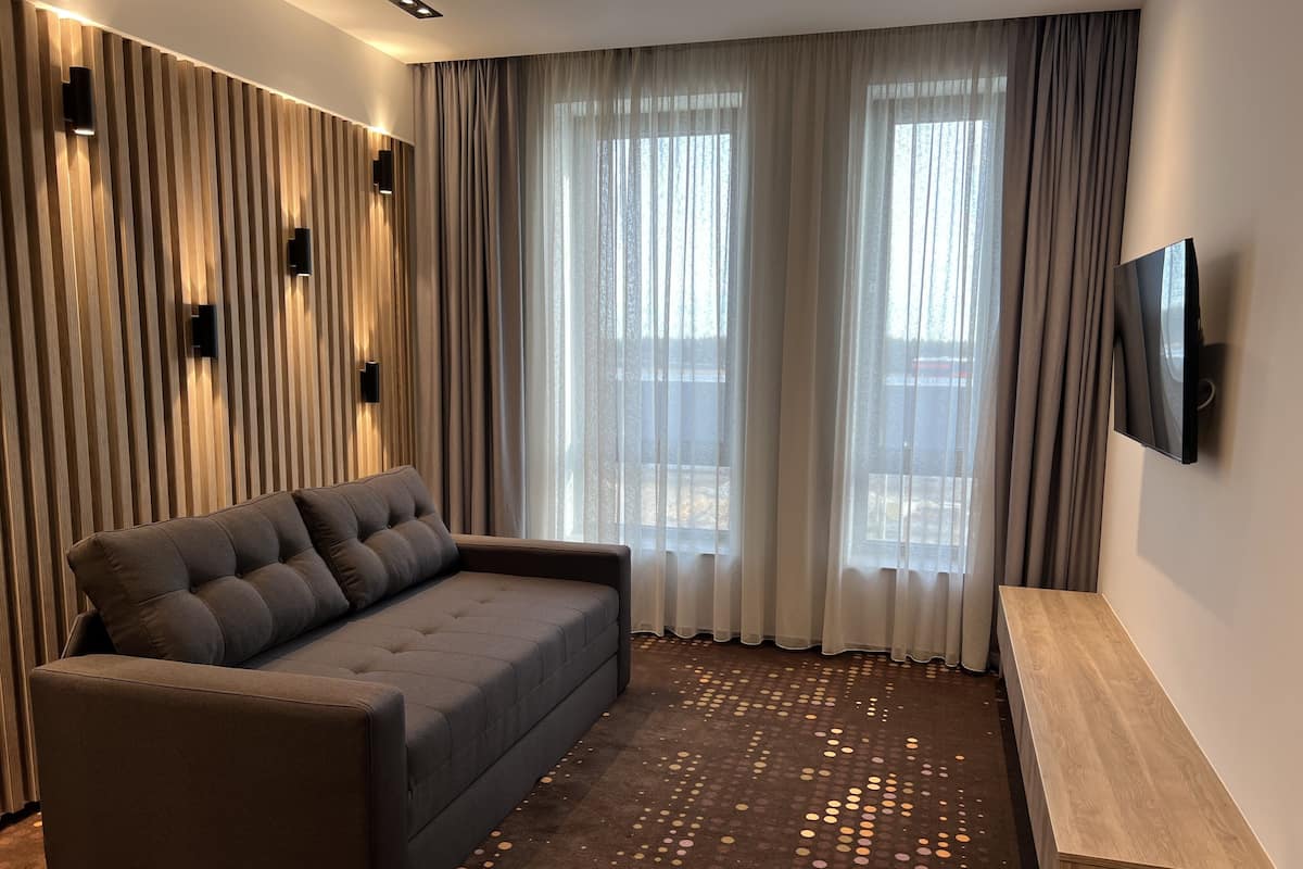 Una sala de estar moderna con un sofá, un televisor montado en la pared y una alfombra estampada.