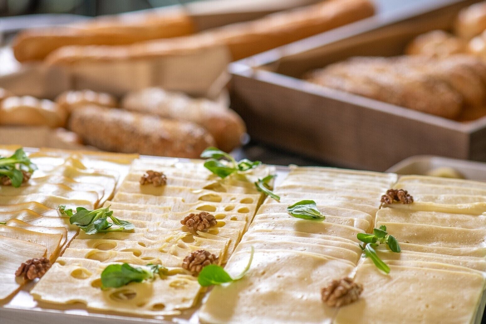 A cheese board with various cheeses, nuts, and herbs.