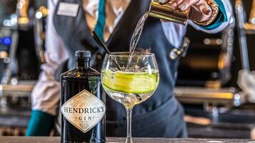 A bartender pouring Hendrick's Gin into a glass with a lime slice.
