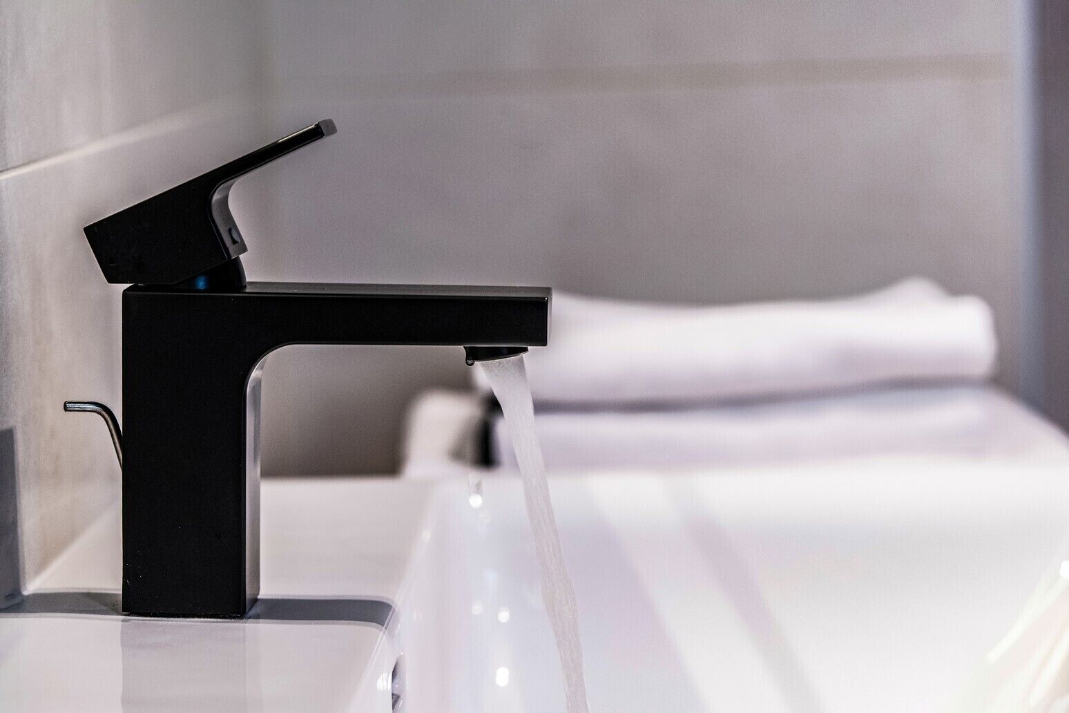 Une salle de bain moderne avec un robinet noir et un lavabo blanc.