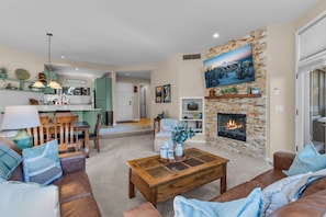 A modern living room with a fireplace, a dining area, and a kitchen.