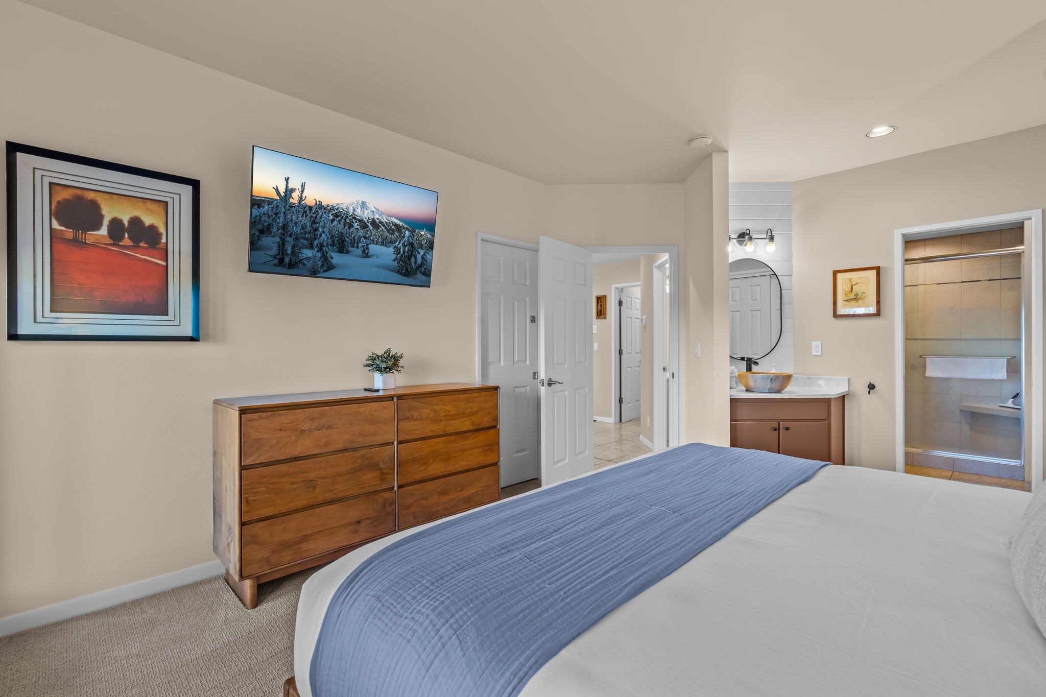 A bedroom with a bed, dresser, and a painting on the wall.