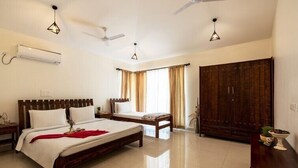 A hotel room with a large bed, a smaller bed, a wardrobe, and a desk with a lamp. - amã Stays & Trails Arcadia, Coorg (Virajpet)