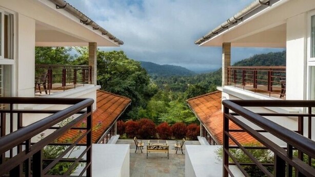 A modern building with two balconies overlooking a lush valley. - amã Stays & Trails Arcadia, Coorg (Virajpet)