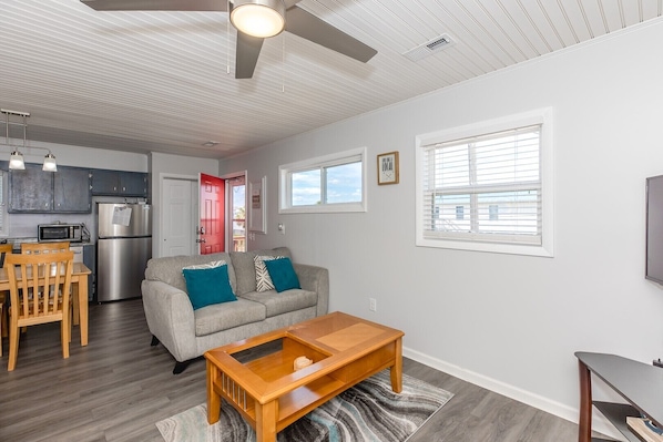 A modern living room with a sofa, coffee table, and dining area. - One Shelluva Day - Cute 3 BR Home in Surf City; Pet Friendly! (Surf City)