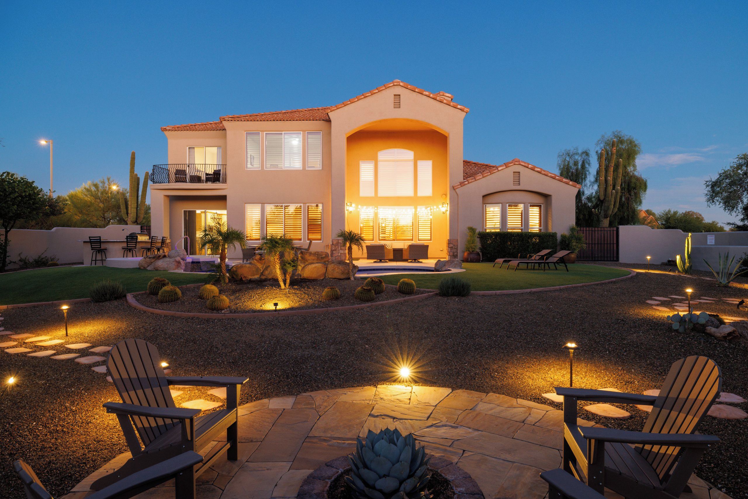 A two-story house with a patio area featuring outdoor seating and a fire pit.