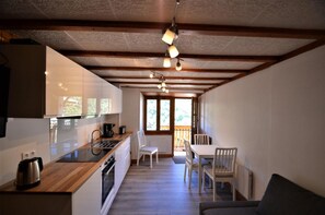A compact kitchen with a wooden countertop, white cabinets, and a dining area with a table and chairs. - Terrace, fireplace or stove, tv, ski locker, 30m², Les Menuires (Saint-Martin-de-Belleville)