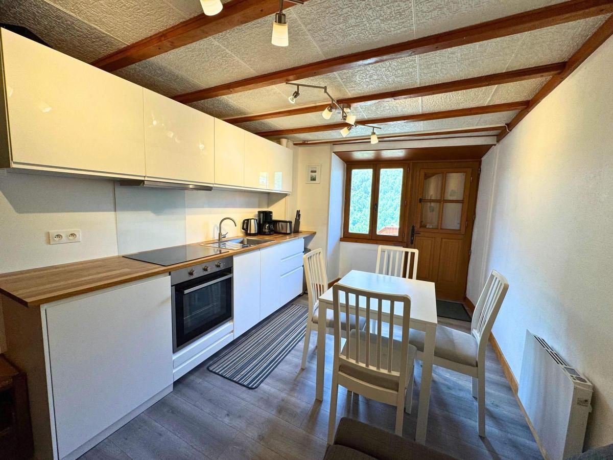 A compact kitchen with white cabinets, a wooden countertop, and a dining area with a table and chairs.
