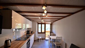A compact kitchen with a wooden countertop, a coffee maker, and a dining area with a table and chairs. - Terrace, fireplace or stove, tv, ski locker, 30m², Les Menuires (Saint-Martin-de-Belleville)