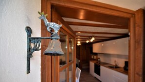 A hallway with wooden beams, a bell, and a decorative deer figure. - Terrace, fireplace or stove, tv, ski locker, 30m², Les Menuires (Saint-Martin-de-Belleville)