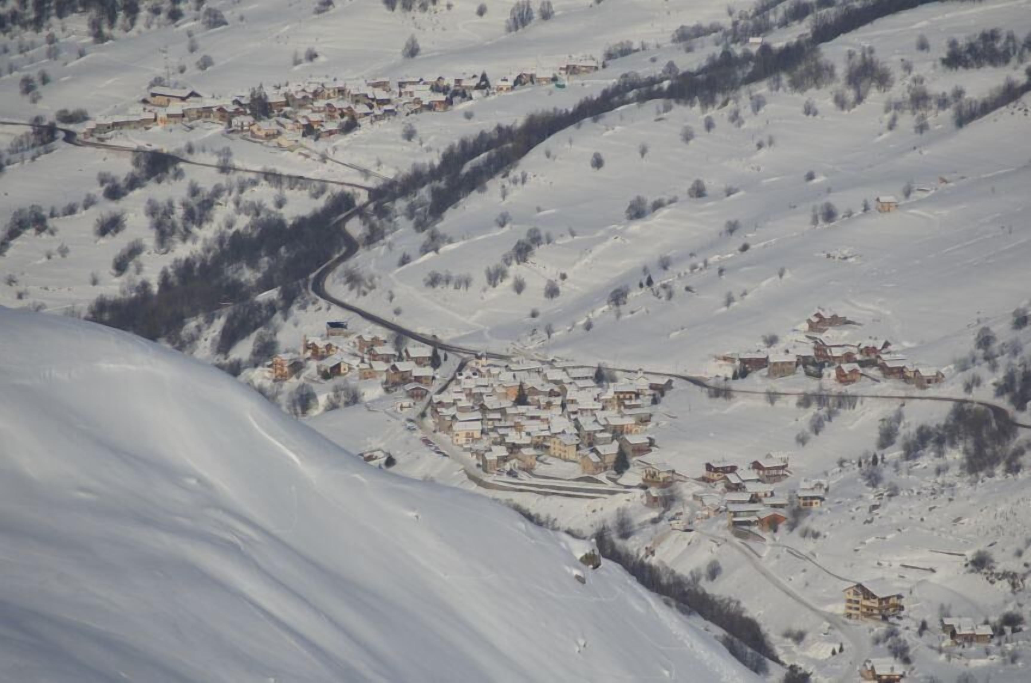 Un villaggio imbiancato dalla neve, con edifici raggruppati lungo una strada tortuosa.