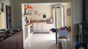 A compact kitchen with white cabinets, a dining area with a table and chairs, and a small refrigerator. - 5'du Barcares, lovely air-conditioned villa with heated pool (ST LAURENT DE LA SALANQUE)