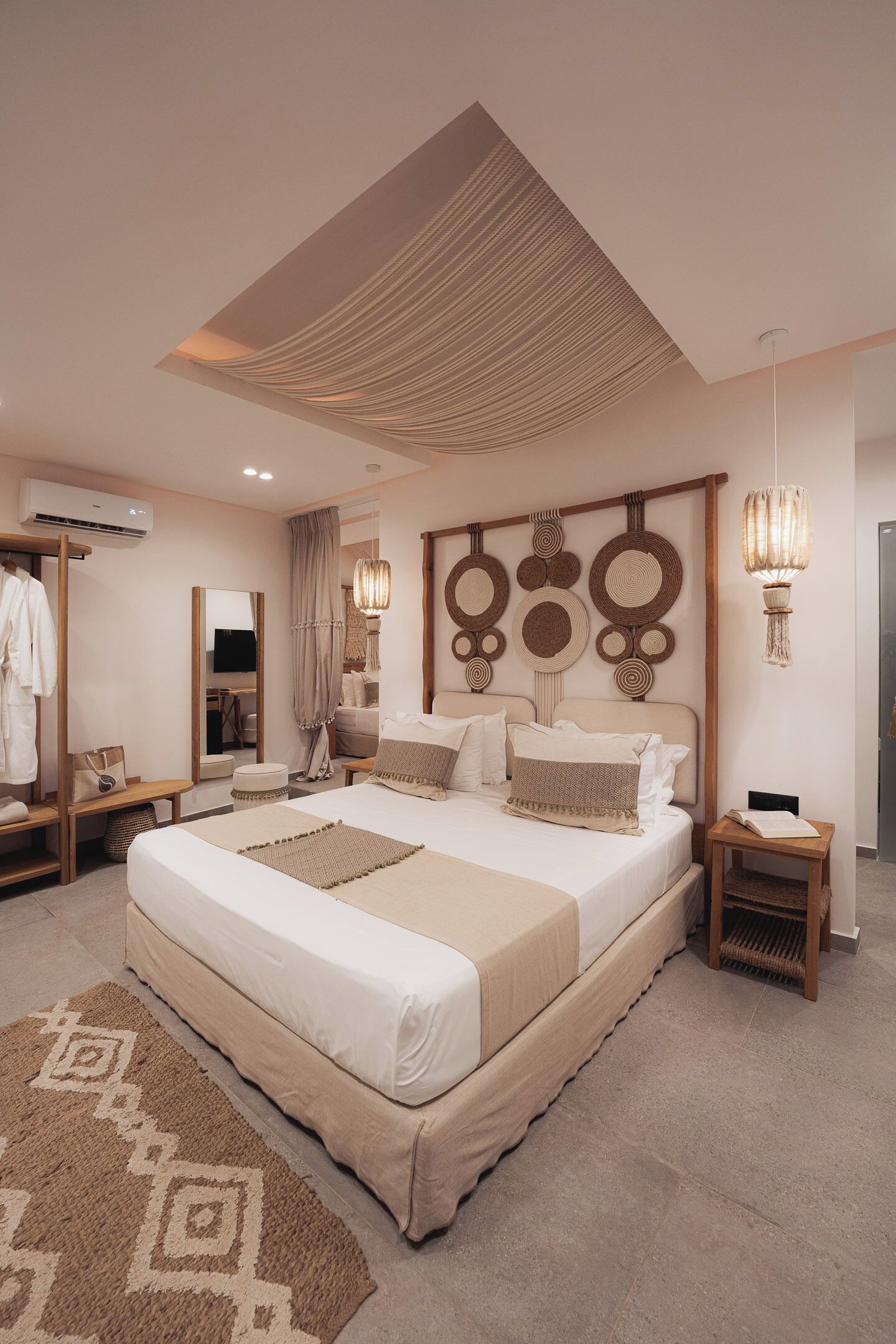 A spacious bedroom with a large bed, a wardrobe, a vanity, and a mirror.