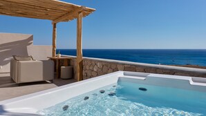 A rooftop terrace with a hot tub, a wooden pergola, a beige sofa, and a view of the ocean. - Armony Suites Milos (Milos)