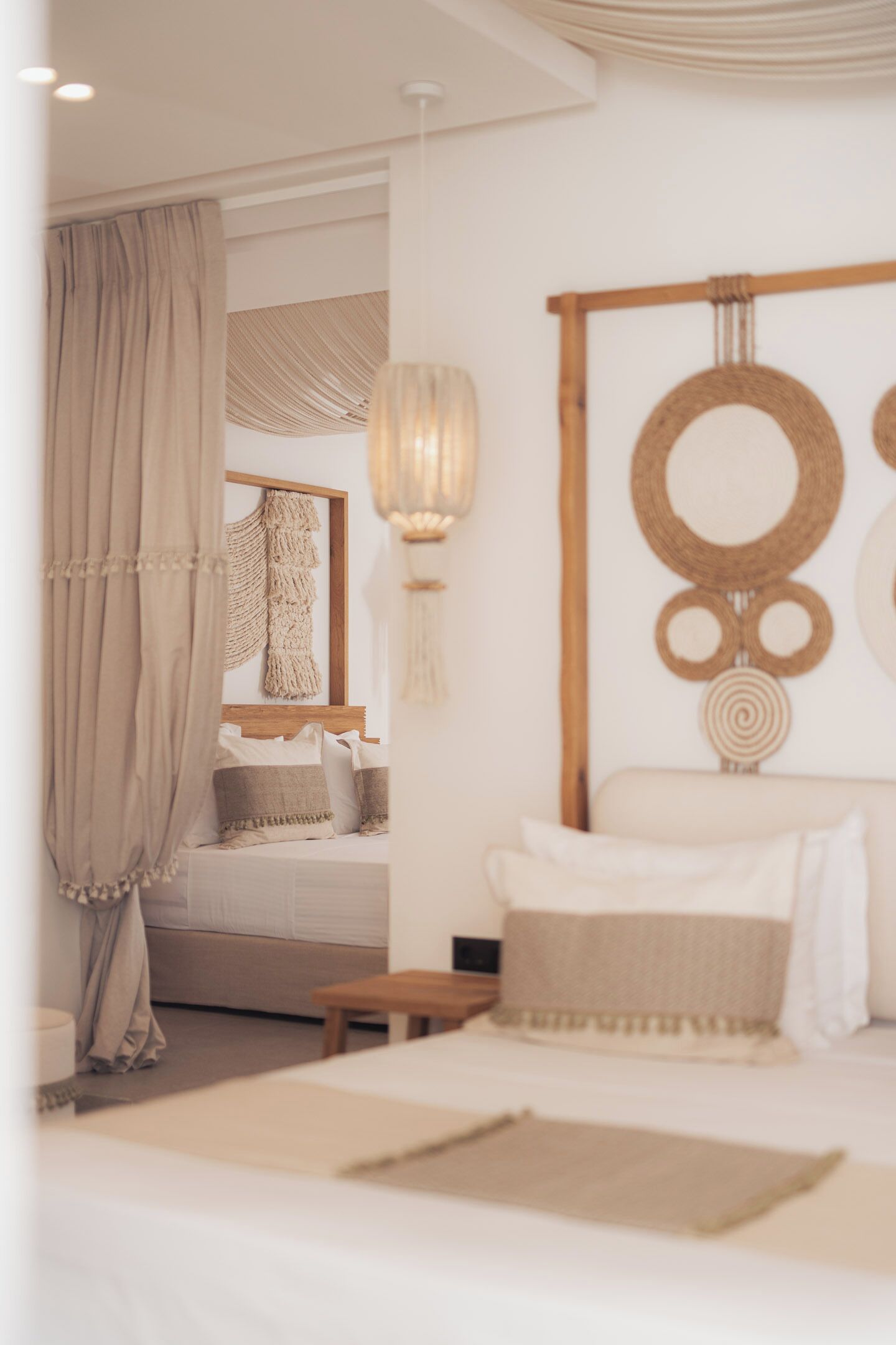 A bedroom with a bed, a wooden headboard, a wall-mounted macrame piece, and a hanging macrame ornament.