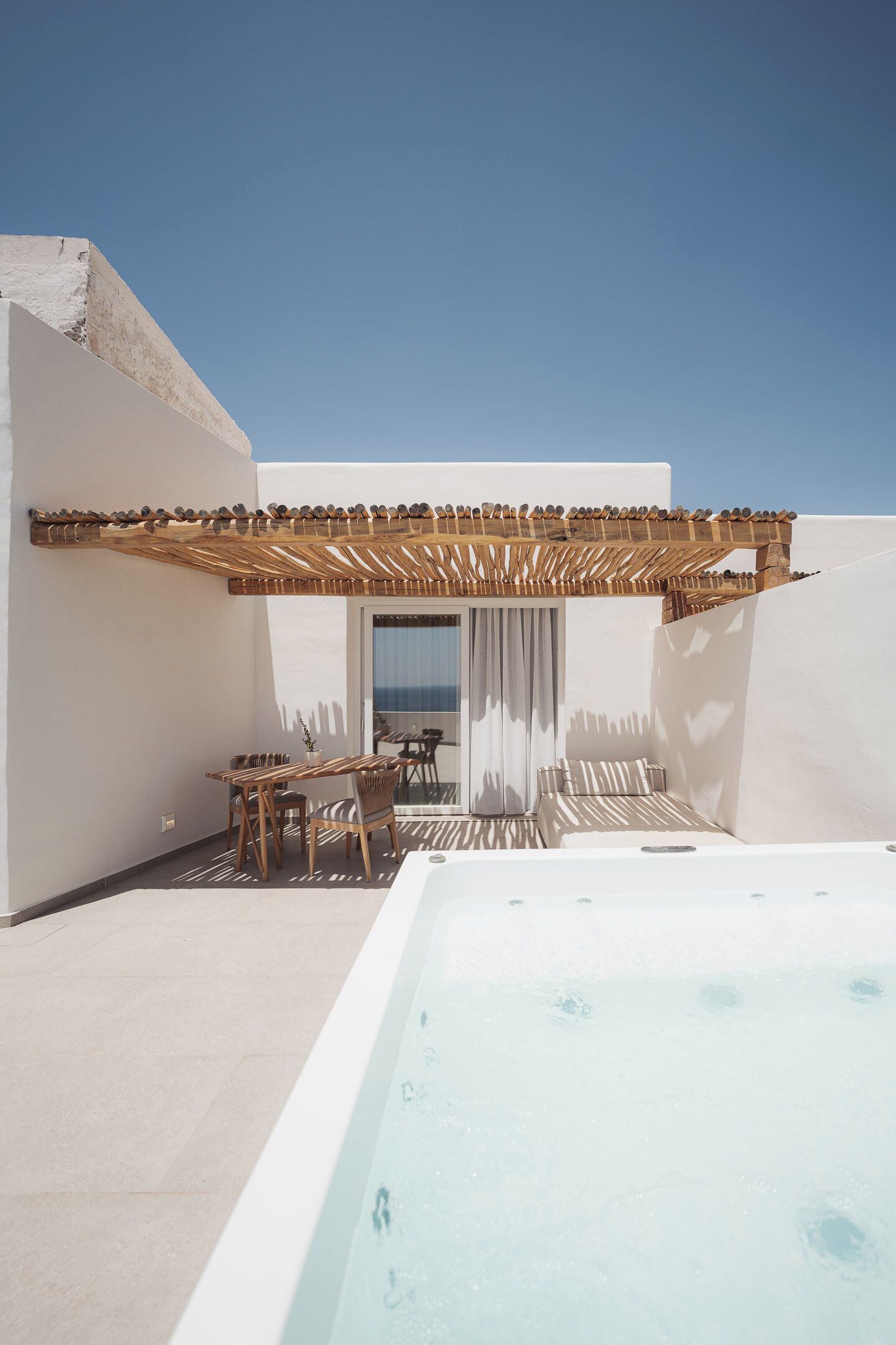 A rooftop terrace with a wooden pergola, a dining area, and a hot tub.