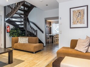 Ein modernes Wohnzimmer mit Treppe, zwei Sofas, einem Couchtisch und einem Gemälde an der Wand.