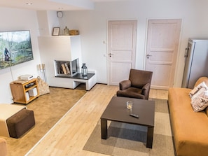 A living room with a sofa, armchair, coffee table, television, fireplace, and a bookshelf.