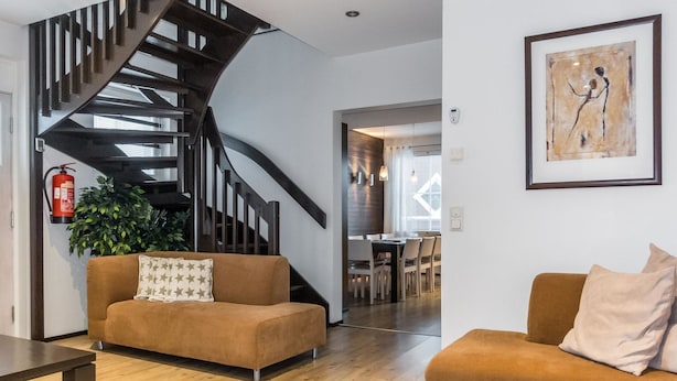 Uma sala de estar moderna com uma escada curva, uma área de jantar e um quadro na parede.