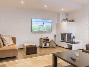 Una sala de estar moderna con un televisor de pantalla plana montado en la pared, un sofá, una mesa de centro y una chimenea.